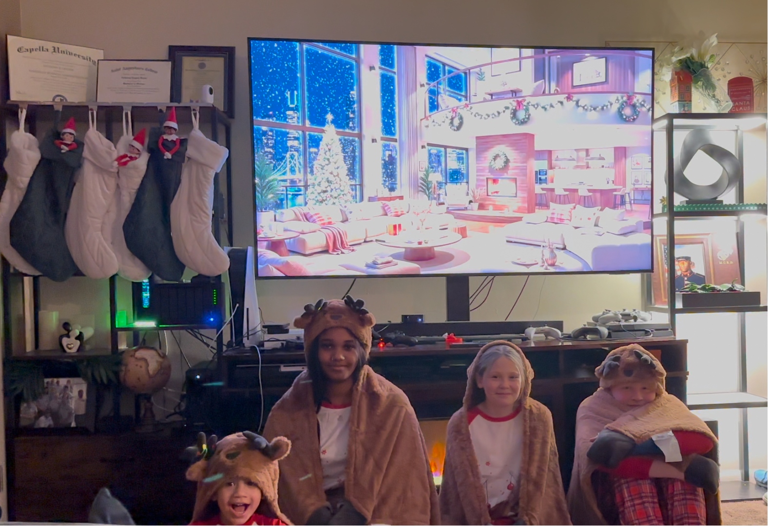 Kids in matching reindeer onesies at Christmas with Capella and Saint Paul's diplomas on the wall.